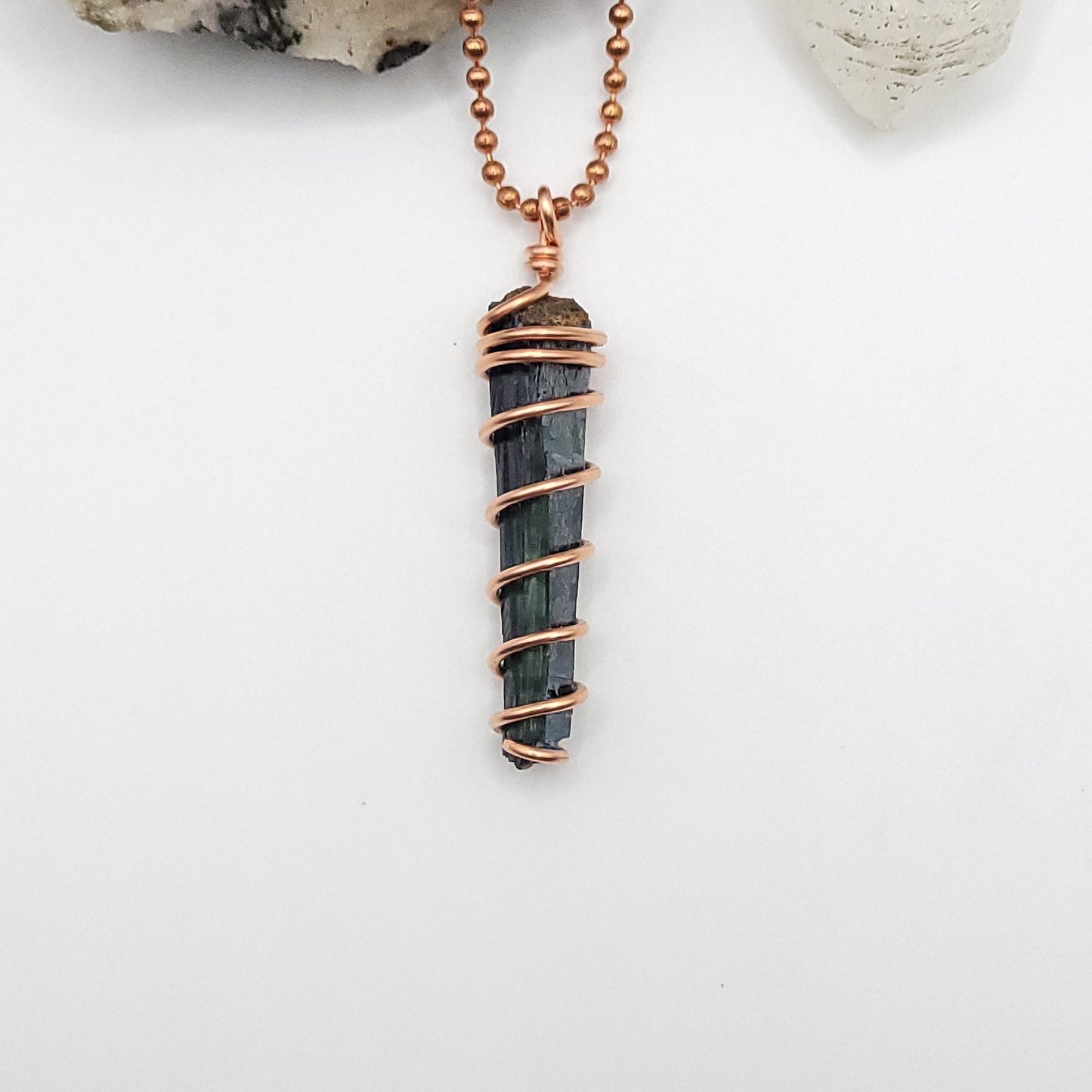 vivianite in copper wire pendant on white background