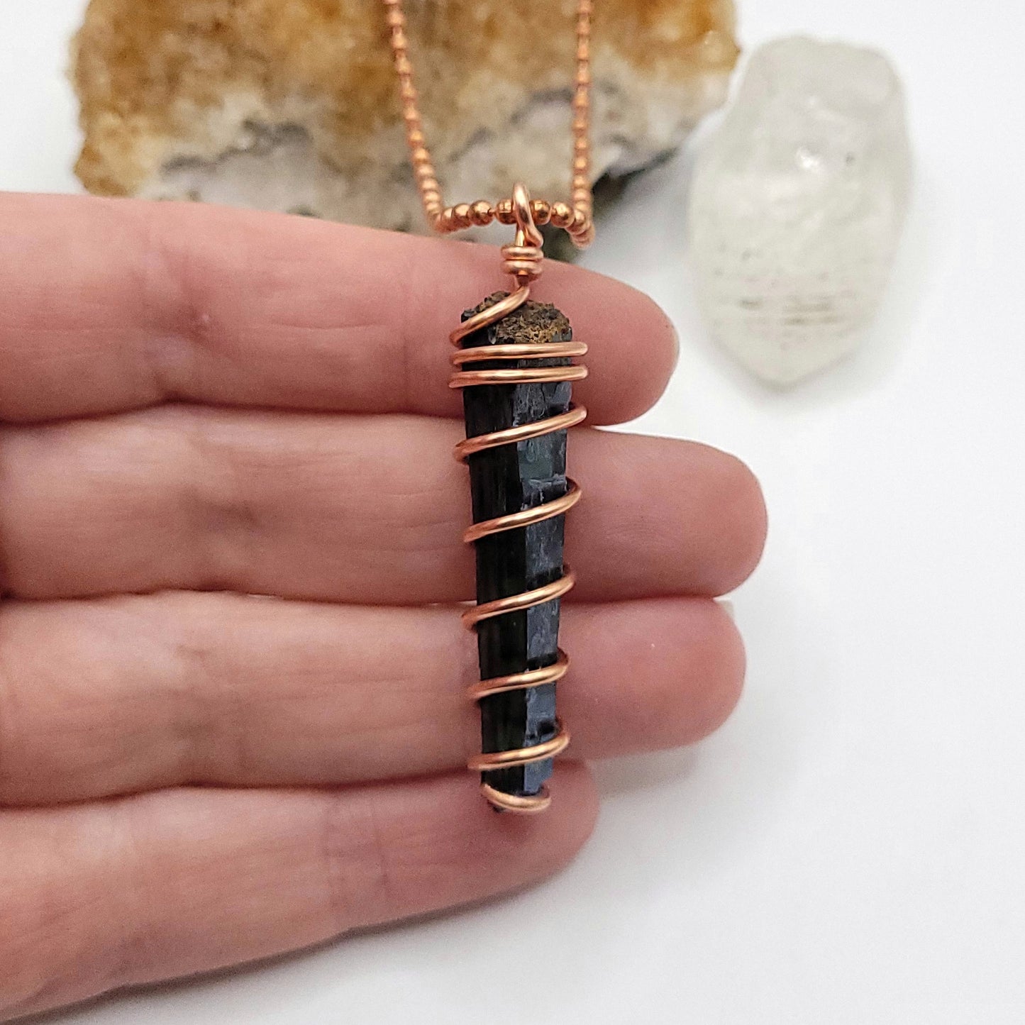 vivianite in copper wire pendant in hand