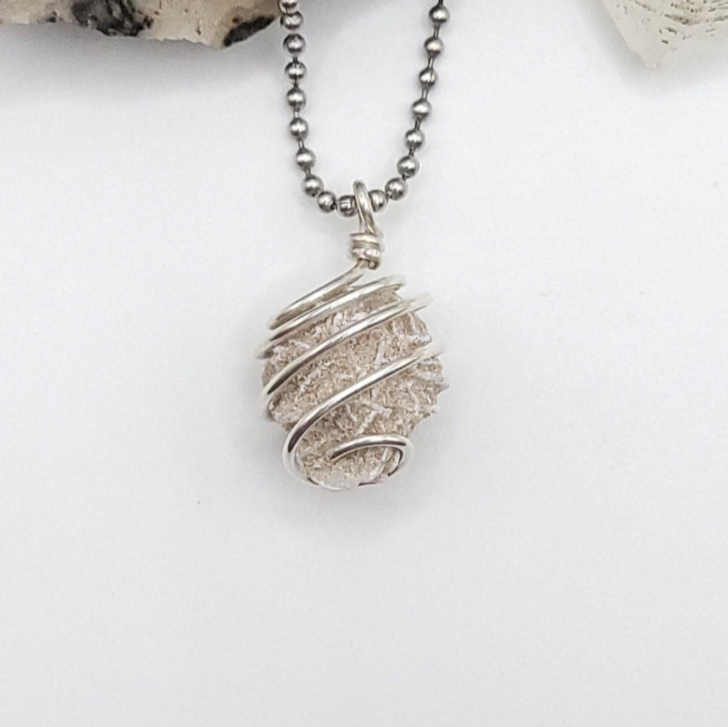 Silver wire-wrapped desert rose selenite pendant necklace on a white background