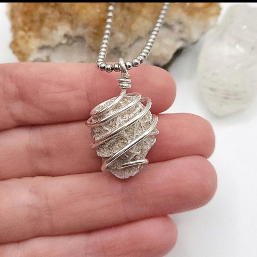 Silver wire-wrapped desert rose selenite pendant necklace held in hand
