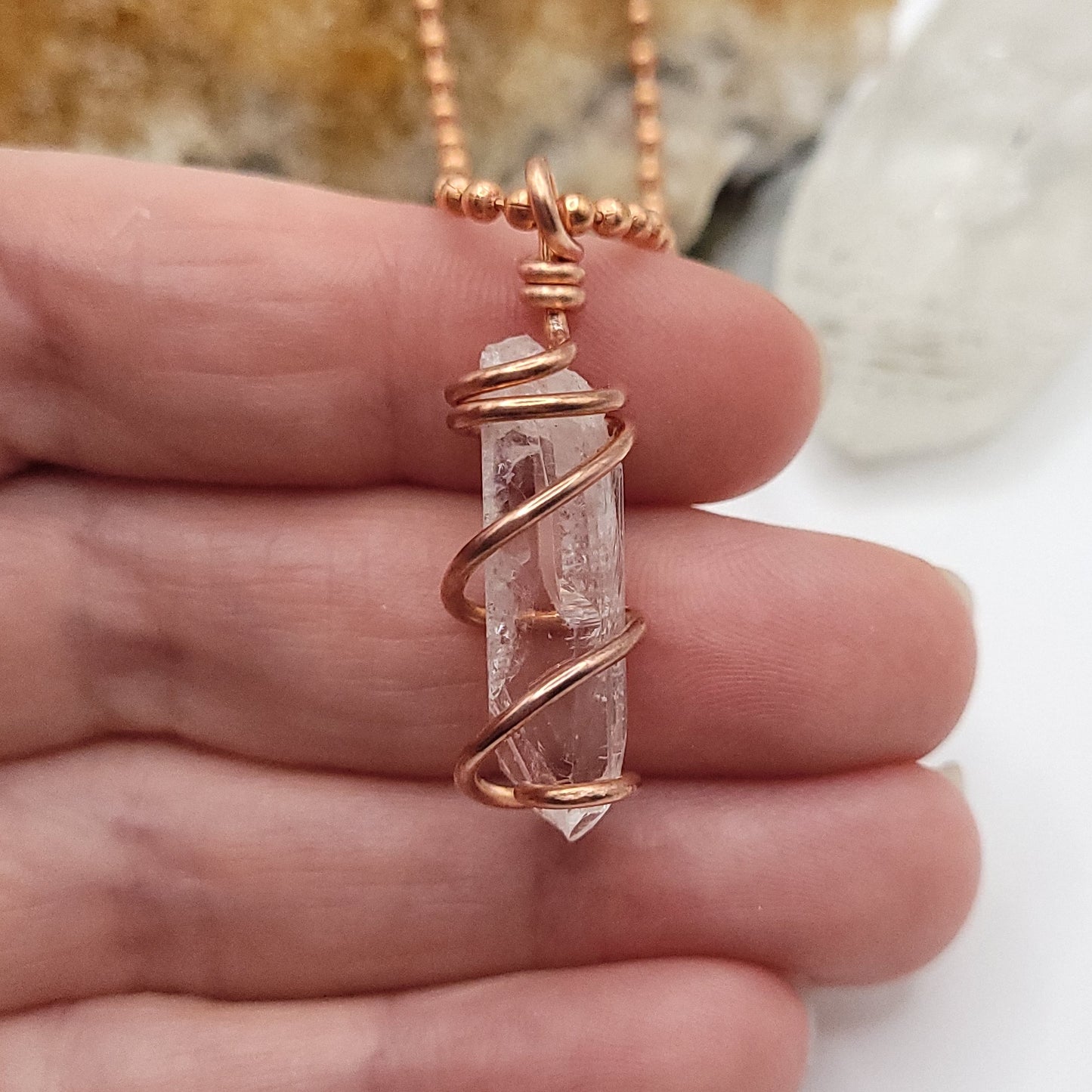 raw danburite pendant in copper close up in hand