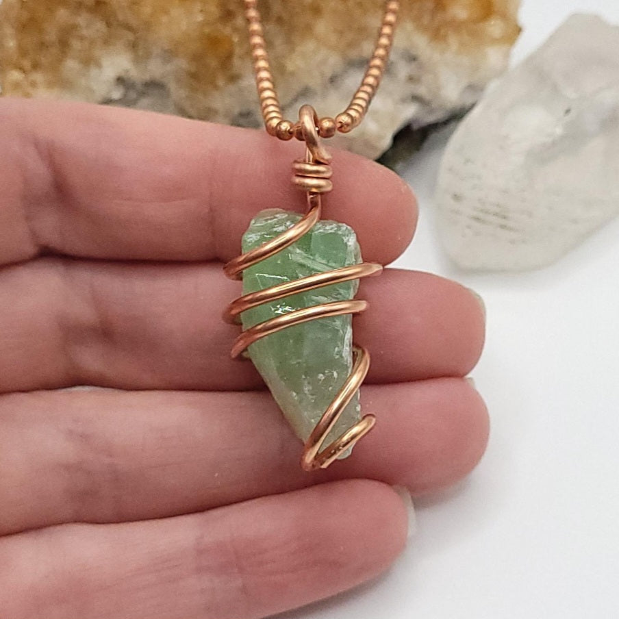 Raw green calcite necklace wrapped in copper, showcasing its healing properties and stylish design.