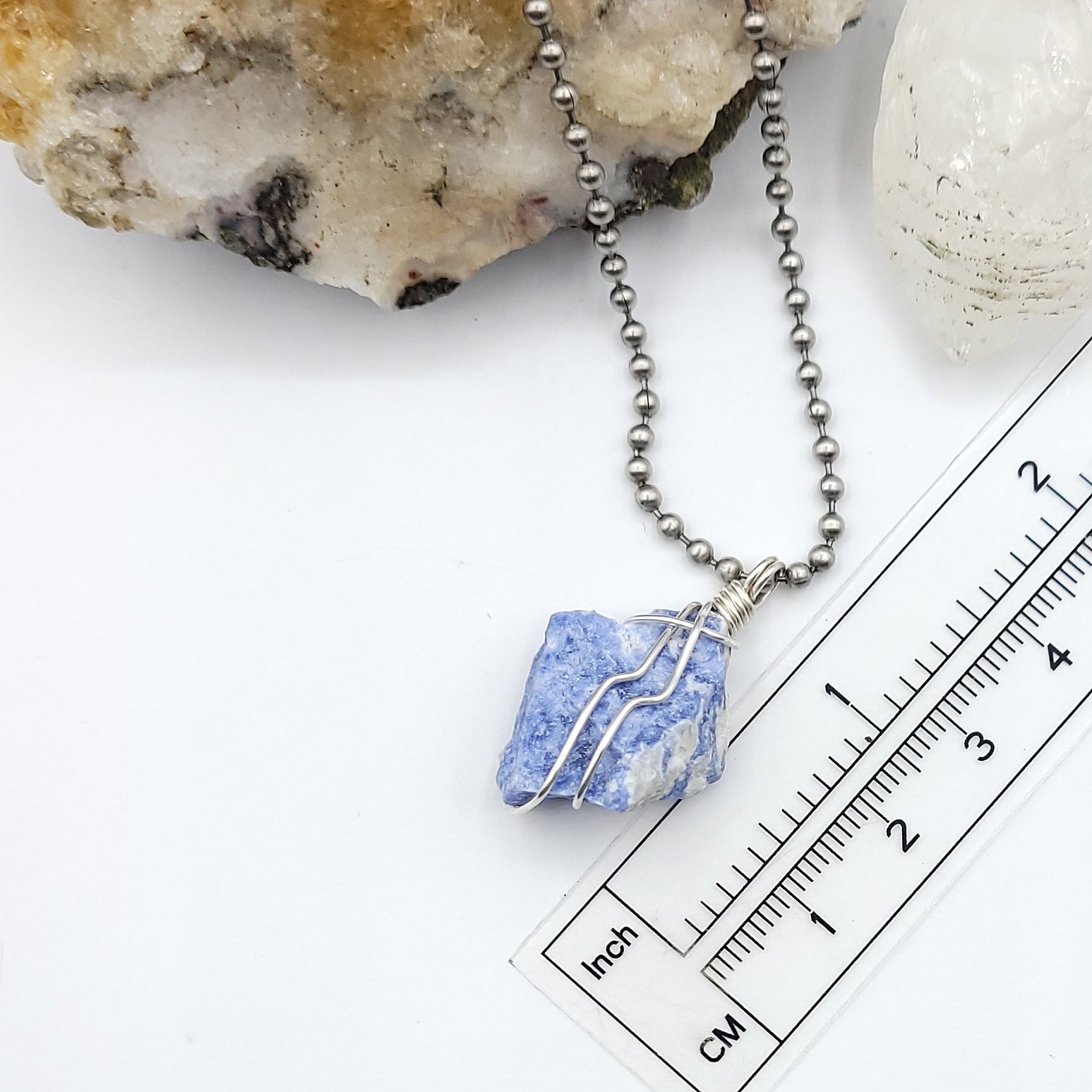 A sodalite crystal wrapped in silver wire with a stainless-steel ball chain measurement just over 1 inch