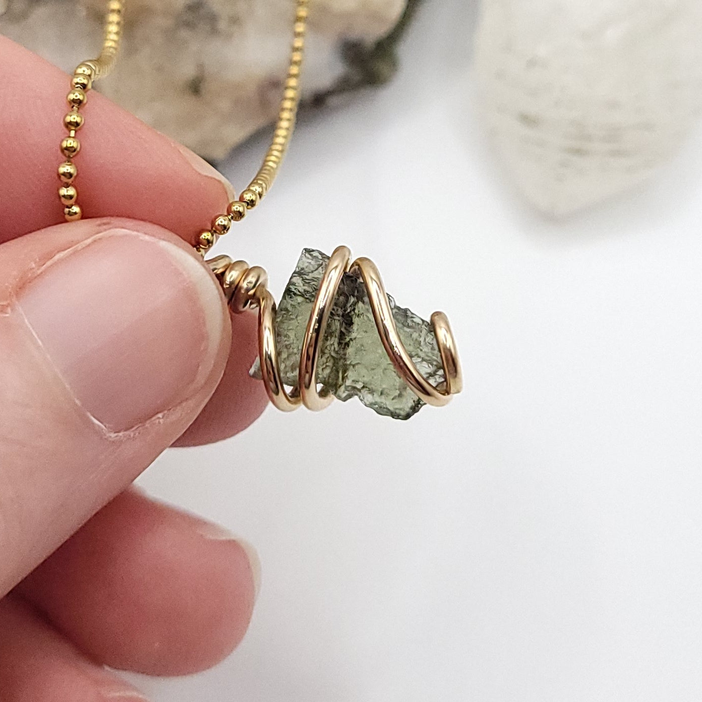 Raw Moldavite Crystal Necklace in gold against the light
