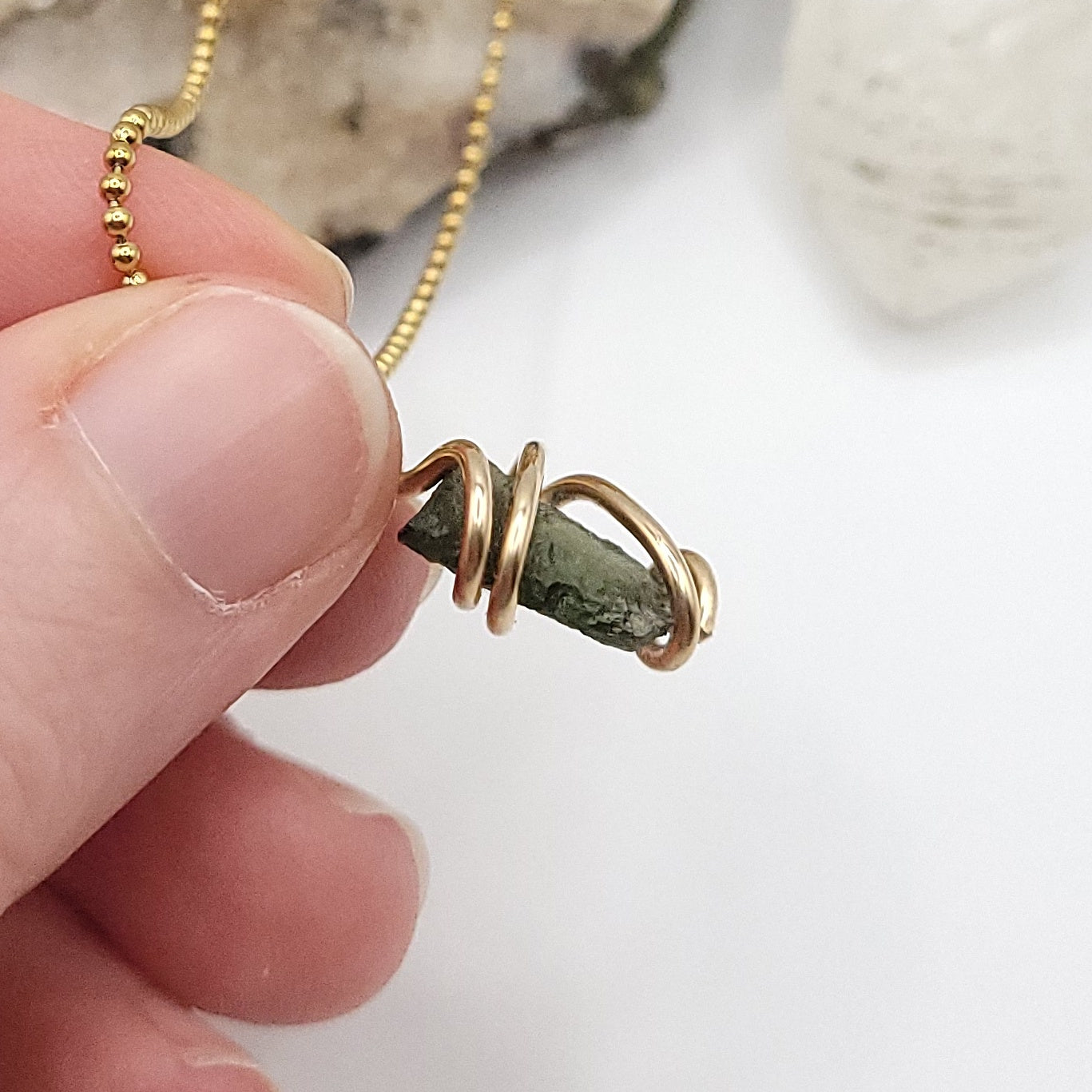 Raw Moldavite Crystal Necklace in gold side view against the light
