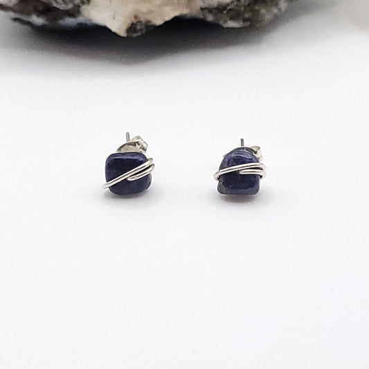 Pair of blue sapphire earrings with silver wire wrapping on a white background
