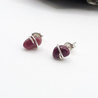 Pair of ruby earrings with silver wire wrapping on a white background