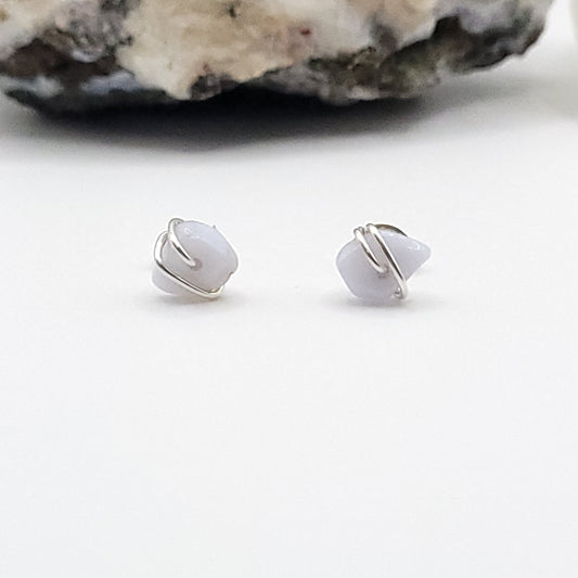 Pair of silver wire wrapped blue lace agate earrings on a white surface.