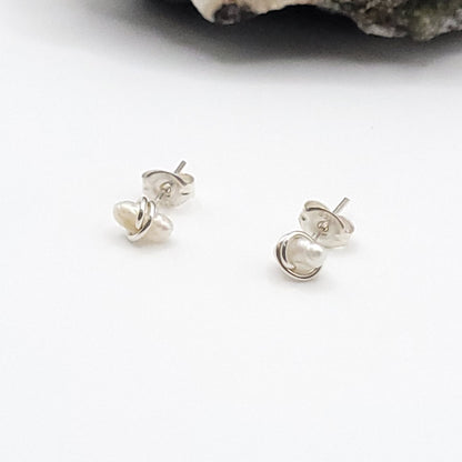 Pair of silver pearl stud earrings on a white background