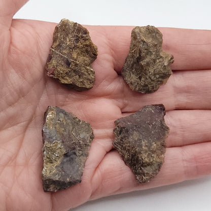 Natural raw Pietersite stones displayed on a hand, showcasing their unique textures and colors.