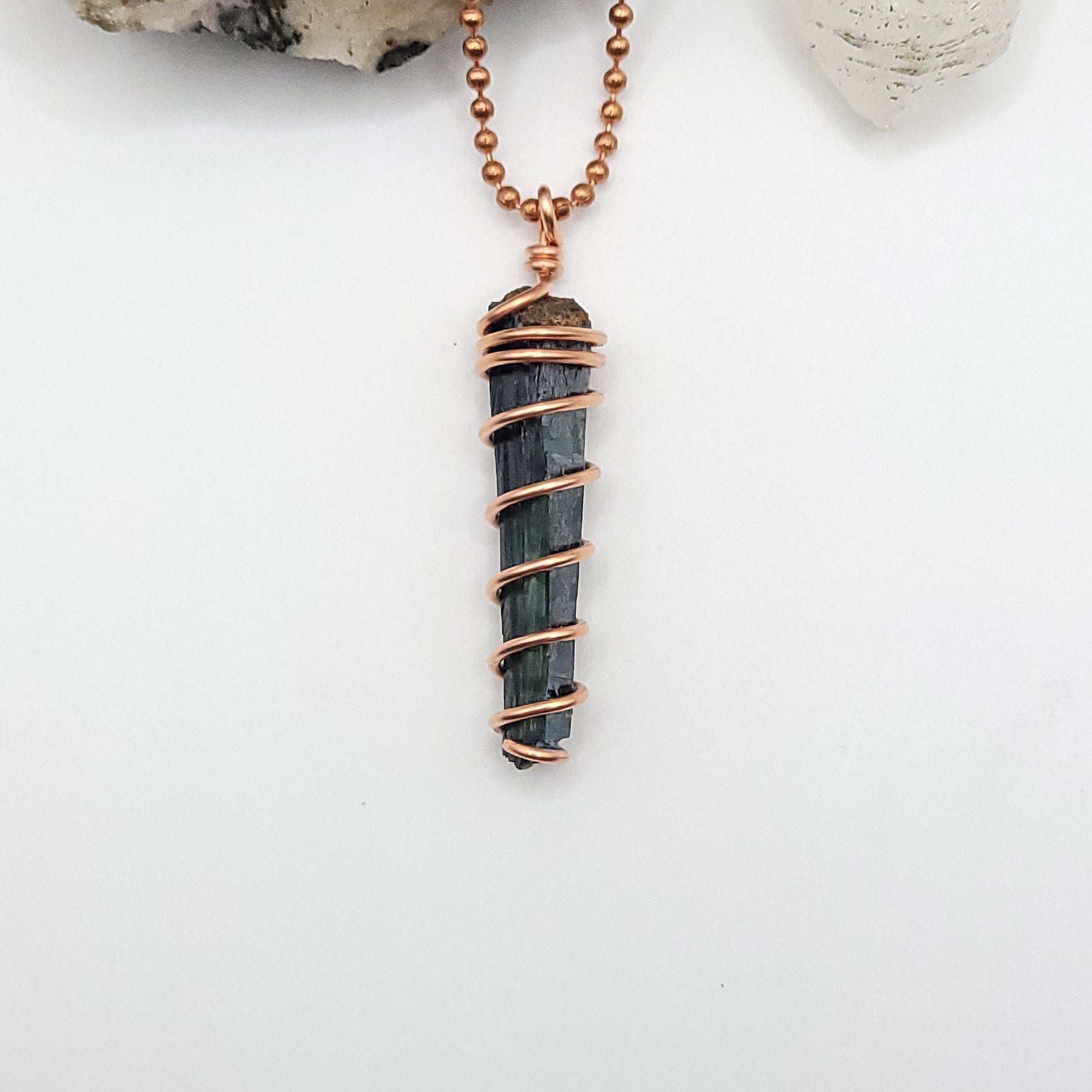 vivianite in copper wire pendant on white background