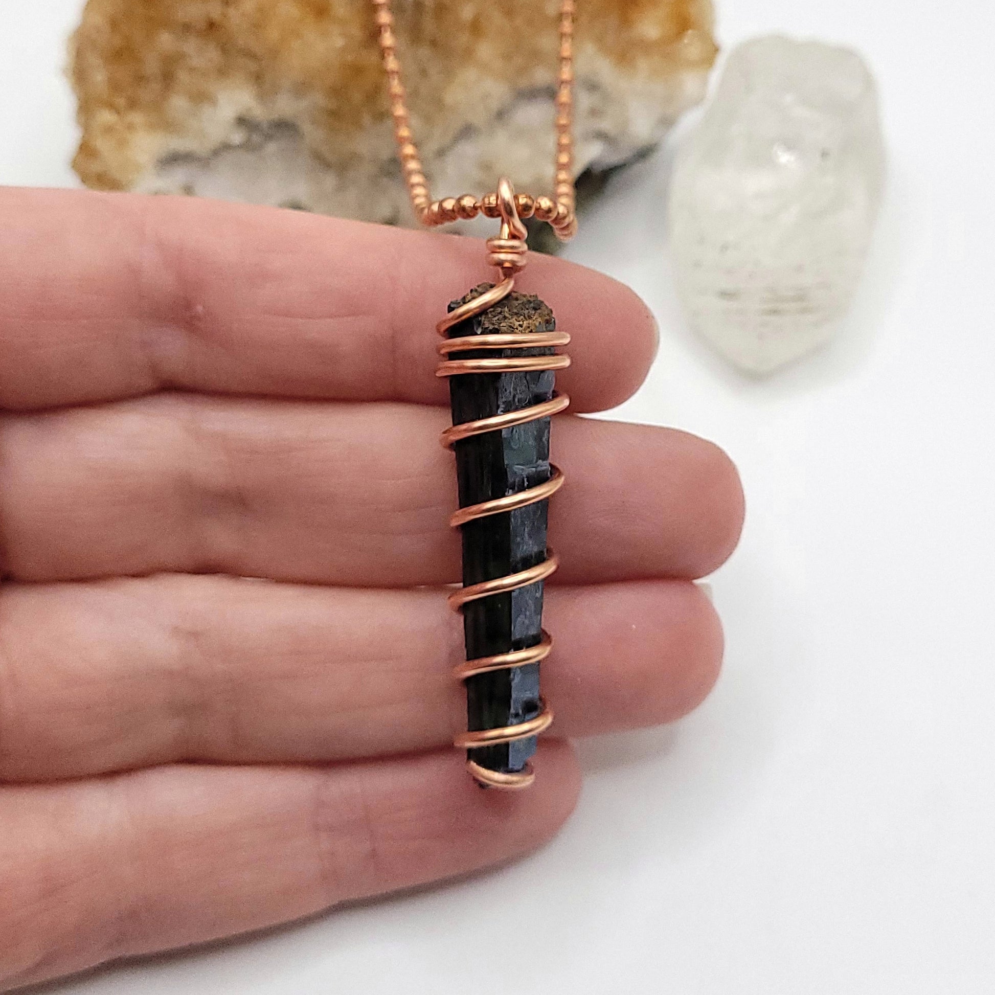 vivianite in copper wire pendant in hand