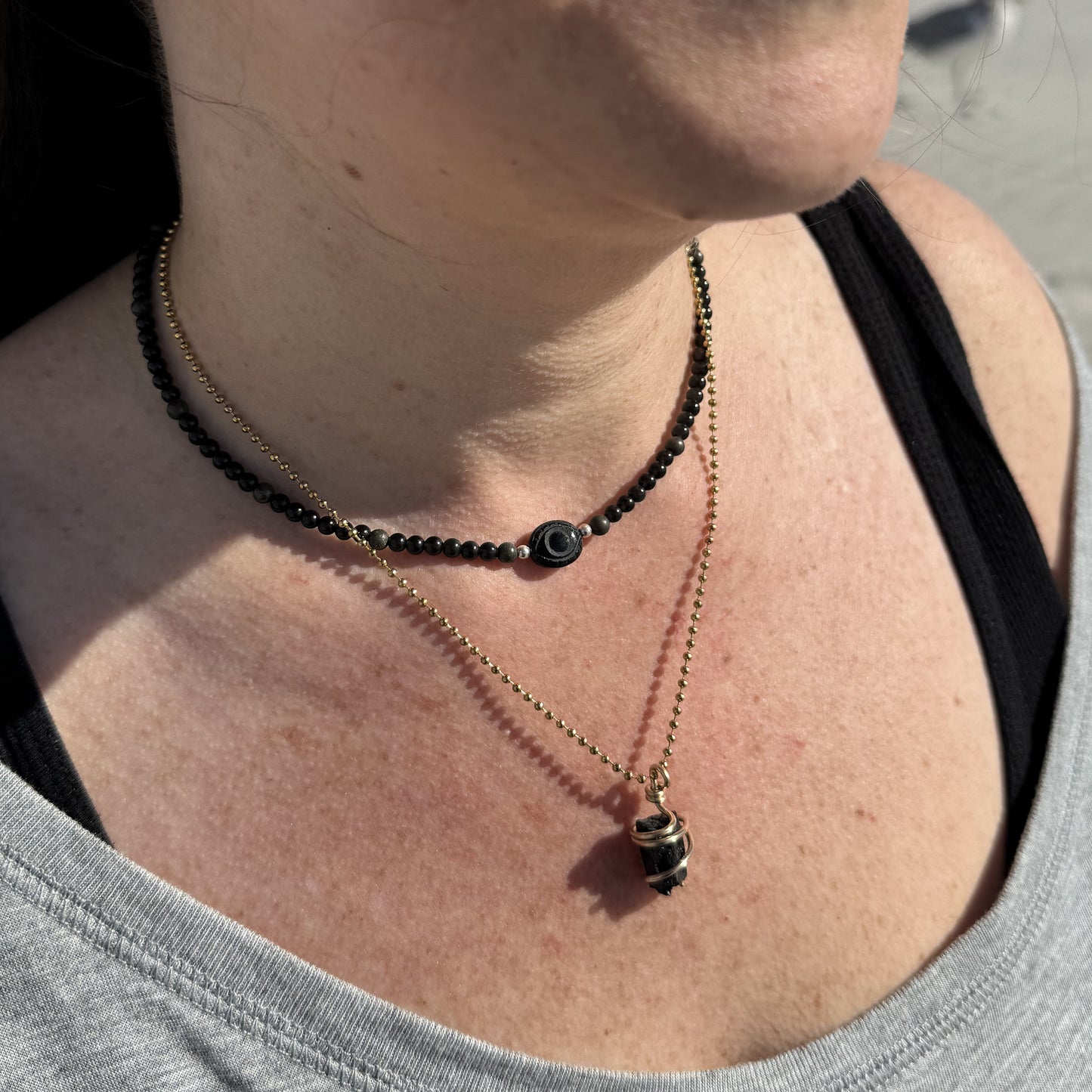 Onyx evil eye necklace layered with obsidian and pyrite beads for protection and balance.