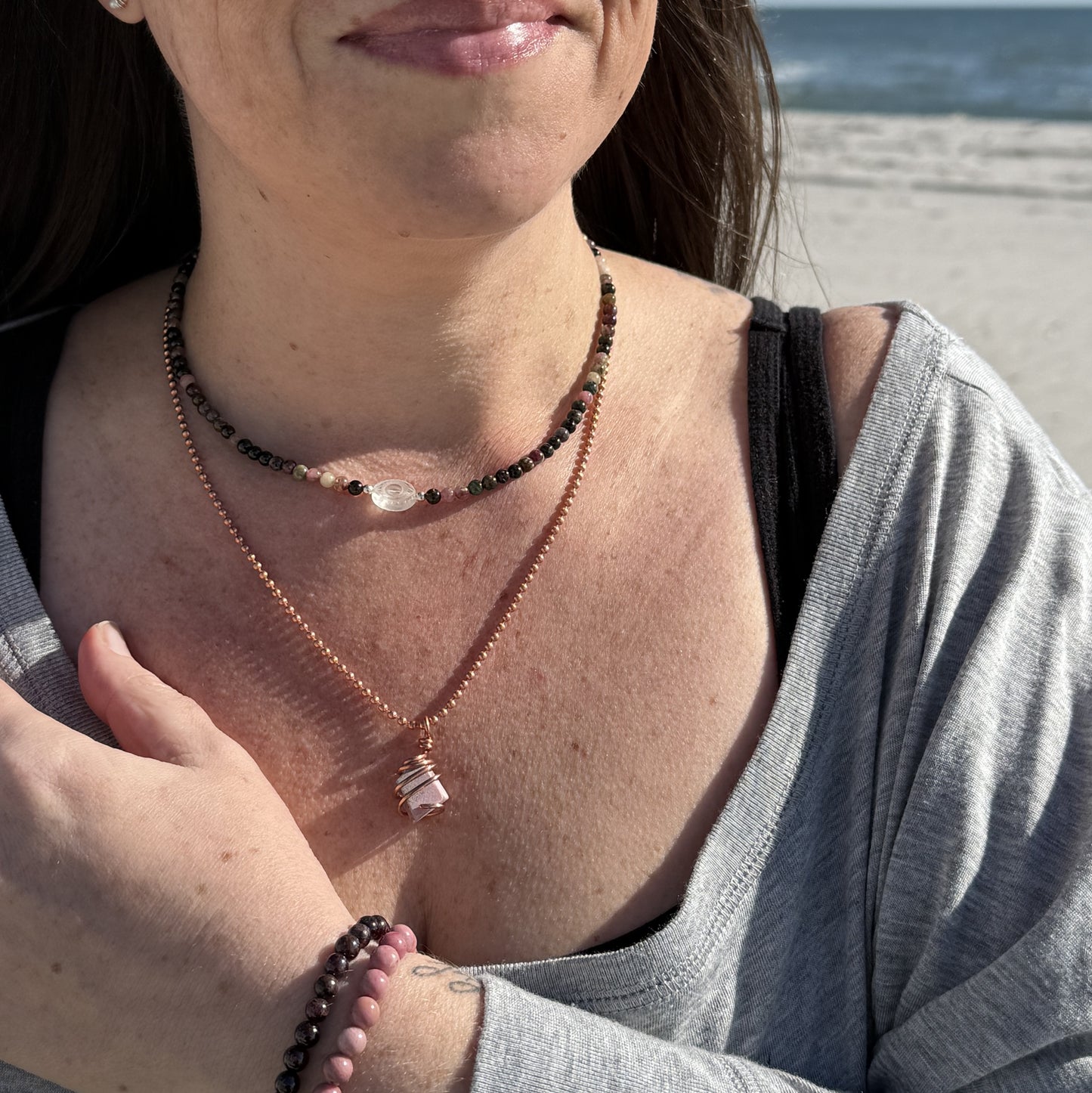 Clear Quartz Evil Eye Necklace showcased with Multi-Color Tourmaline on a beach setting, enhancing energy balance and protection.