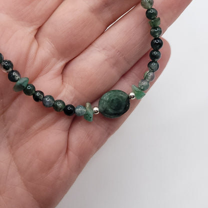 Emerald Evil Eye Necklace featuring Green Moss Agate and Emerald chip beads, held in a hand for scale.