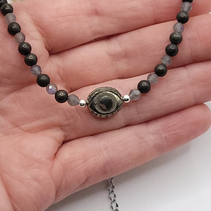 Pyrite evil eye necklace shown in hand with protective beads, designed for crystal energy and intuitive strength.