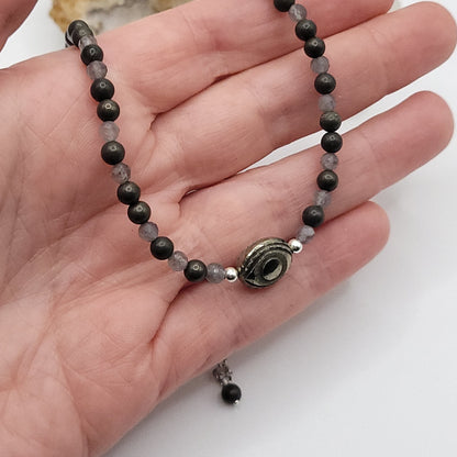Pyrite Evil Eye Necklace displayed in a hand with Pyrite and Labradorite beads for protective strength.