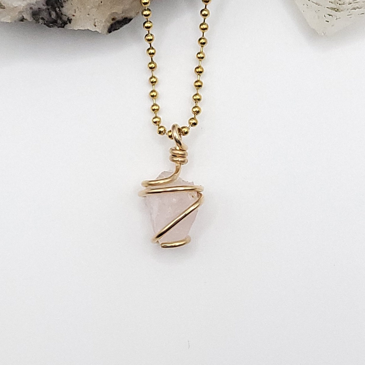 raw rose quartz necklace wrapped in gold, showcasing the loving energy of rose quartz.