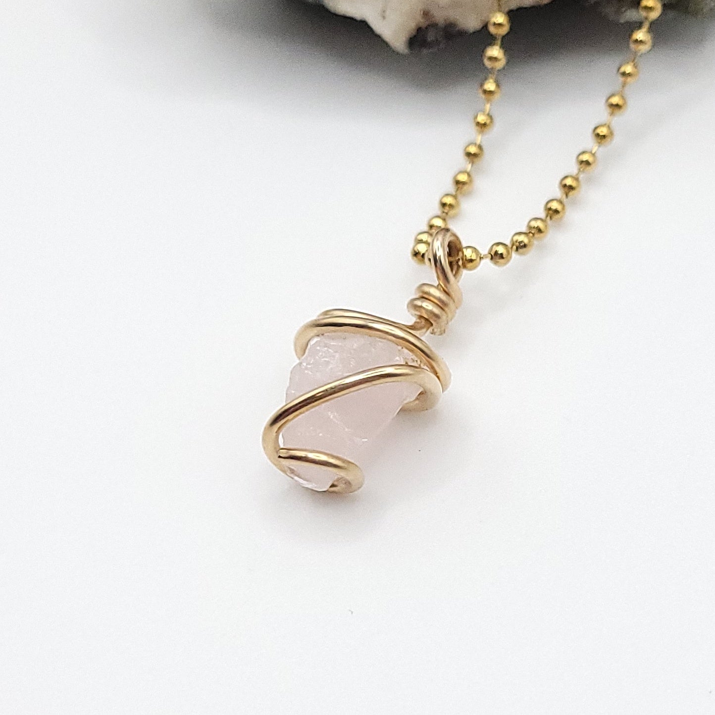 Raw Rose Quartz necklace in gold filled wire, showcasing its soft pink stone and compassion energy.