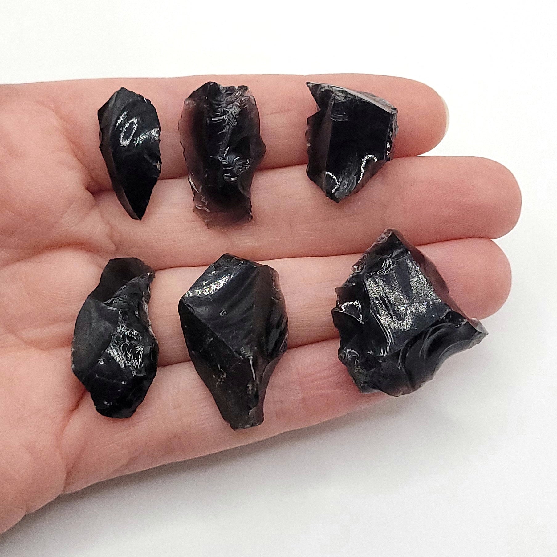 6 pieces of raw black obsidian in hand for a raw obsidian necklace in copper