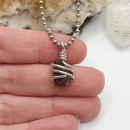Raw Moldavite Necklace in Silver in hand.