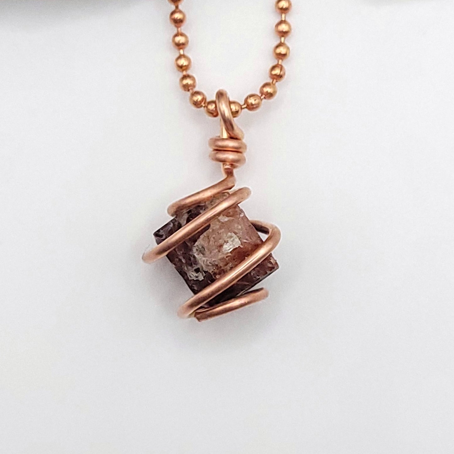 Raw zircon necklace wrapped in copper wire, promoting clarity and inner strength.