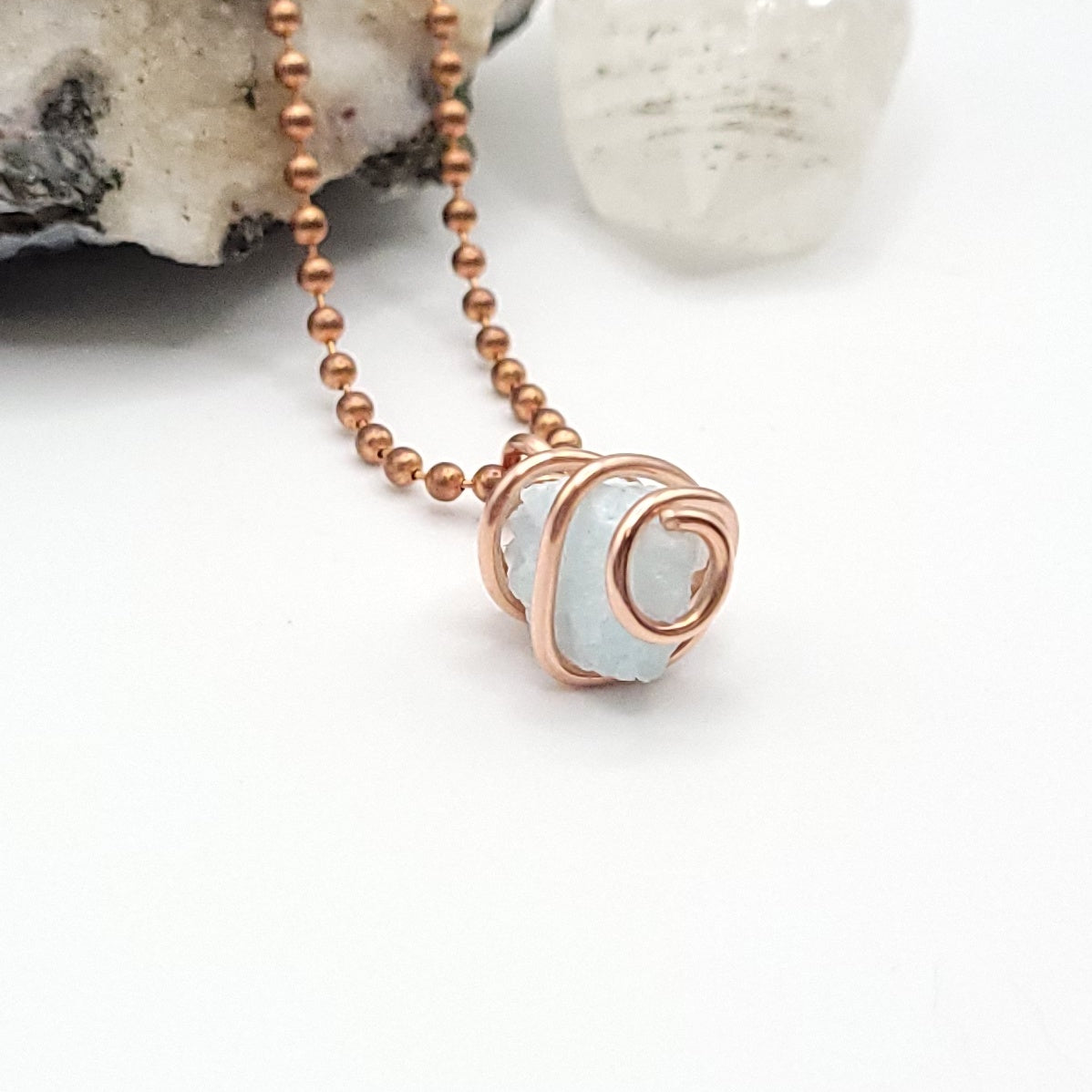Raw blue aragonite necklace wrapped in pure copper wire with copper ball chain on a display.