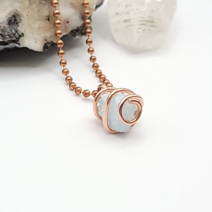 Raw blue aragonite necklace wrapped in pure copper wire with copper ball chain on a display.
