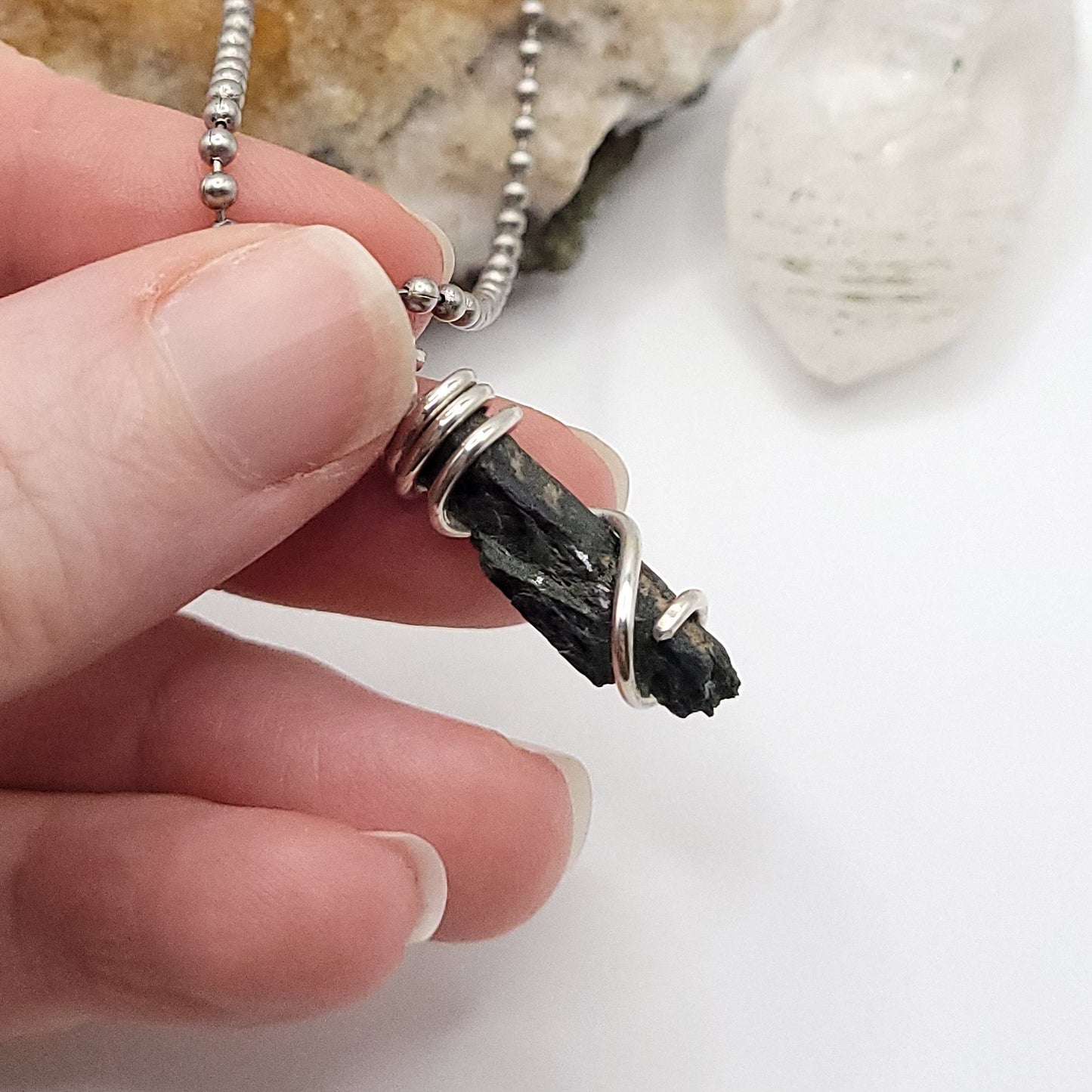 raw aegirine necklace in silver held in hand, showcasing crystal for protection and grounding