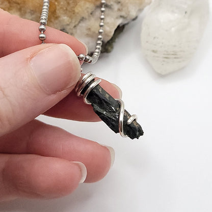 raw aegirine necklace in silver held in hand, showcasing crystal for protection and grounding
