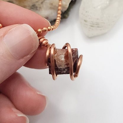 Raw zircon necklace wrapped in copper wire, showcasing the mineral's unique clarity and strength.