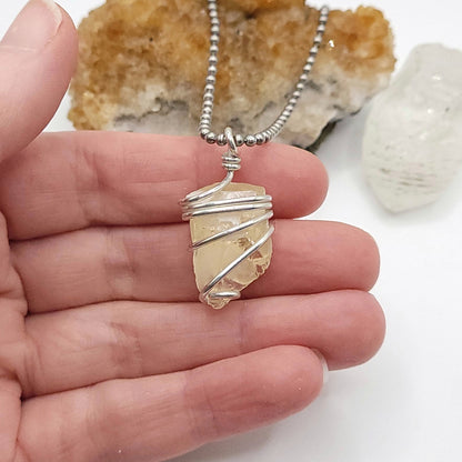 Raw Honey Calcite Necklace in Silver held in hand, showcasing the unique crystal for confidence and motivation.